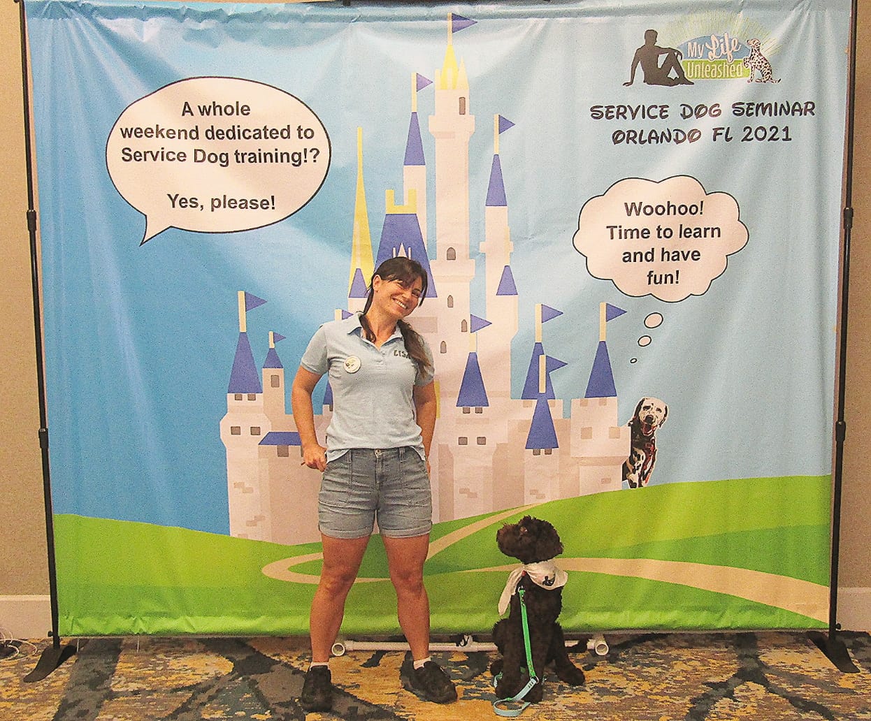 Trainer and dog pose in front of seminar panel
